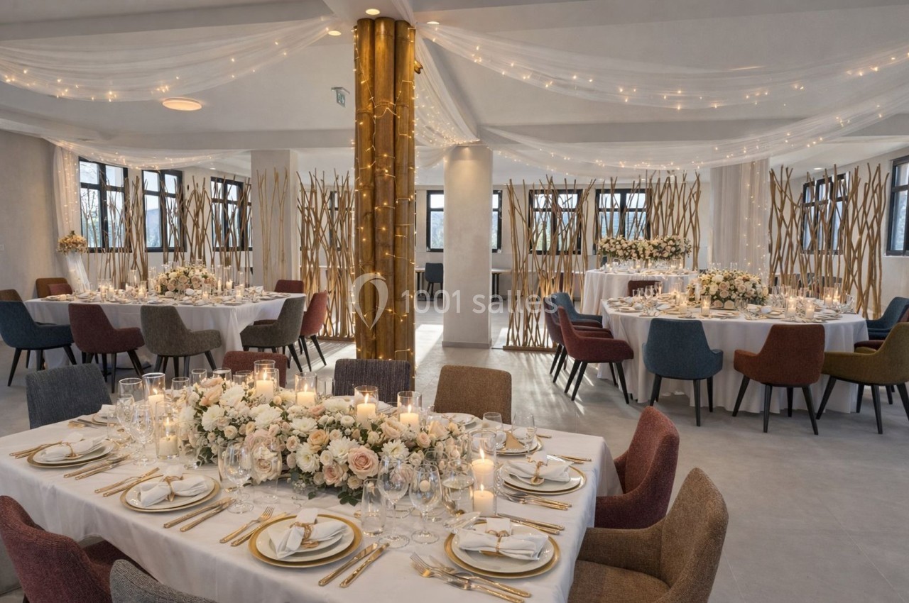Salle de réception décorée pour un mariage avec tables dressées, fleurs, bougies et guirlandes lumineuses.