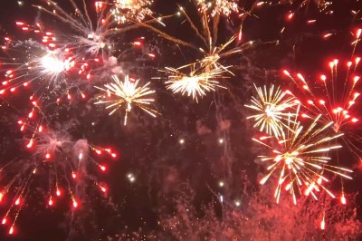 Feux d'artifice multicolores illuminant le ciel nocturne avec des éclats rouges, dorés et scintillants.