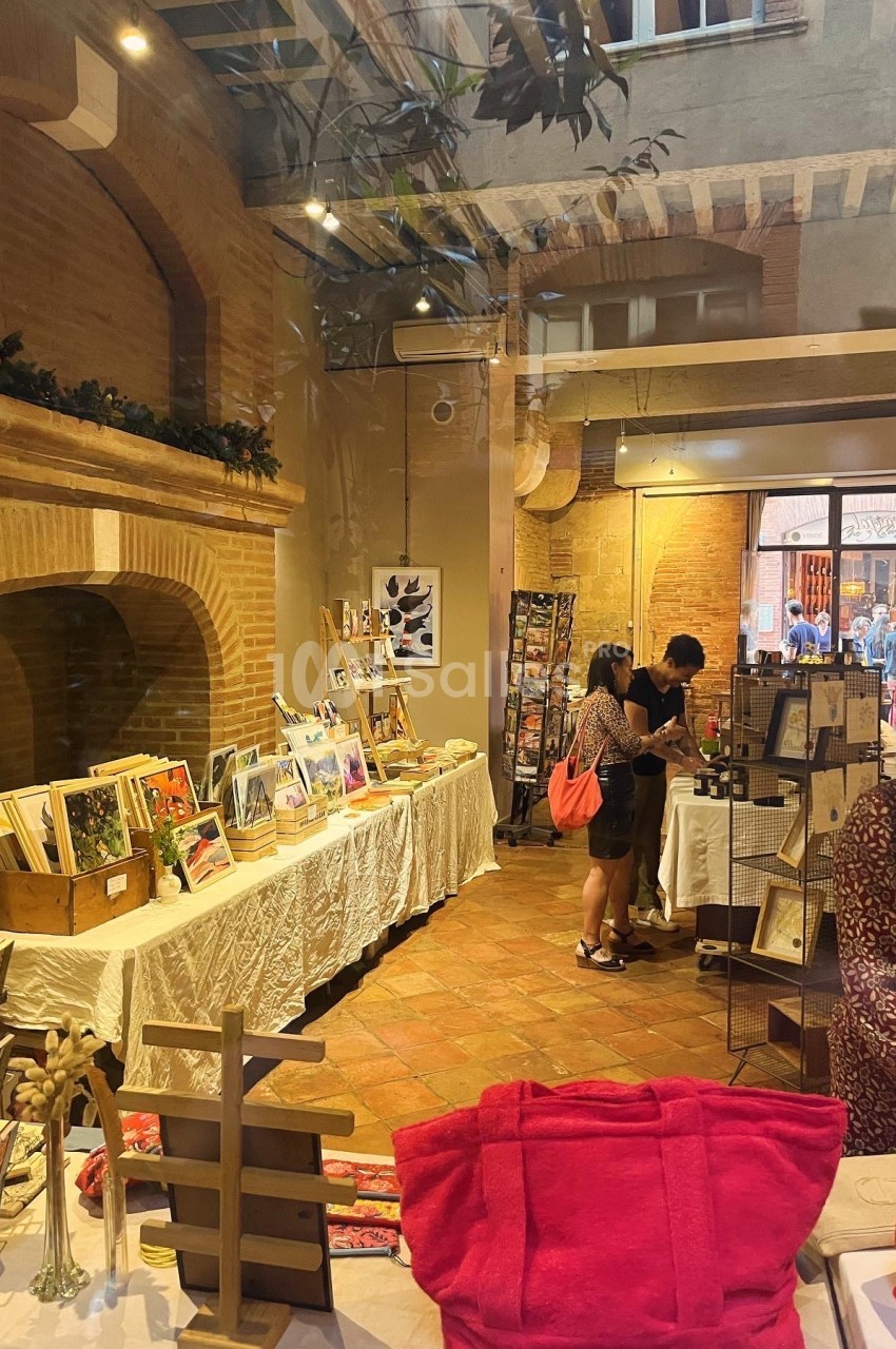 Vue intérieure d'une boutique artisanale avec des tables exposant des œuvres d'art et des clients discutant.