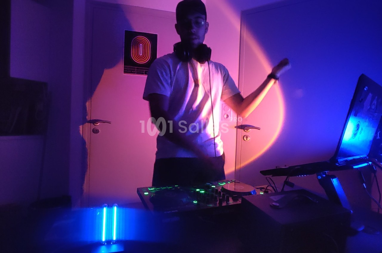 DJ à sa console dans un intérieur éclairé aux lumières néon roses et bleues.