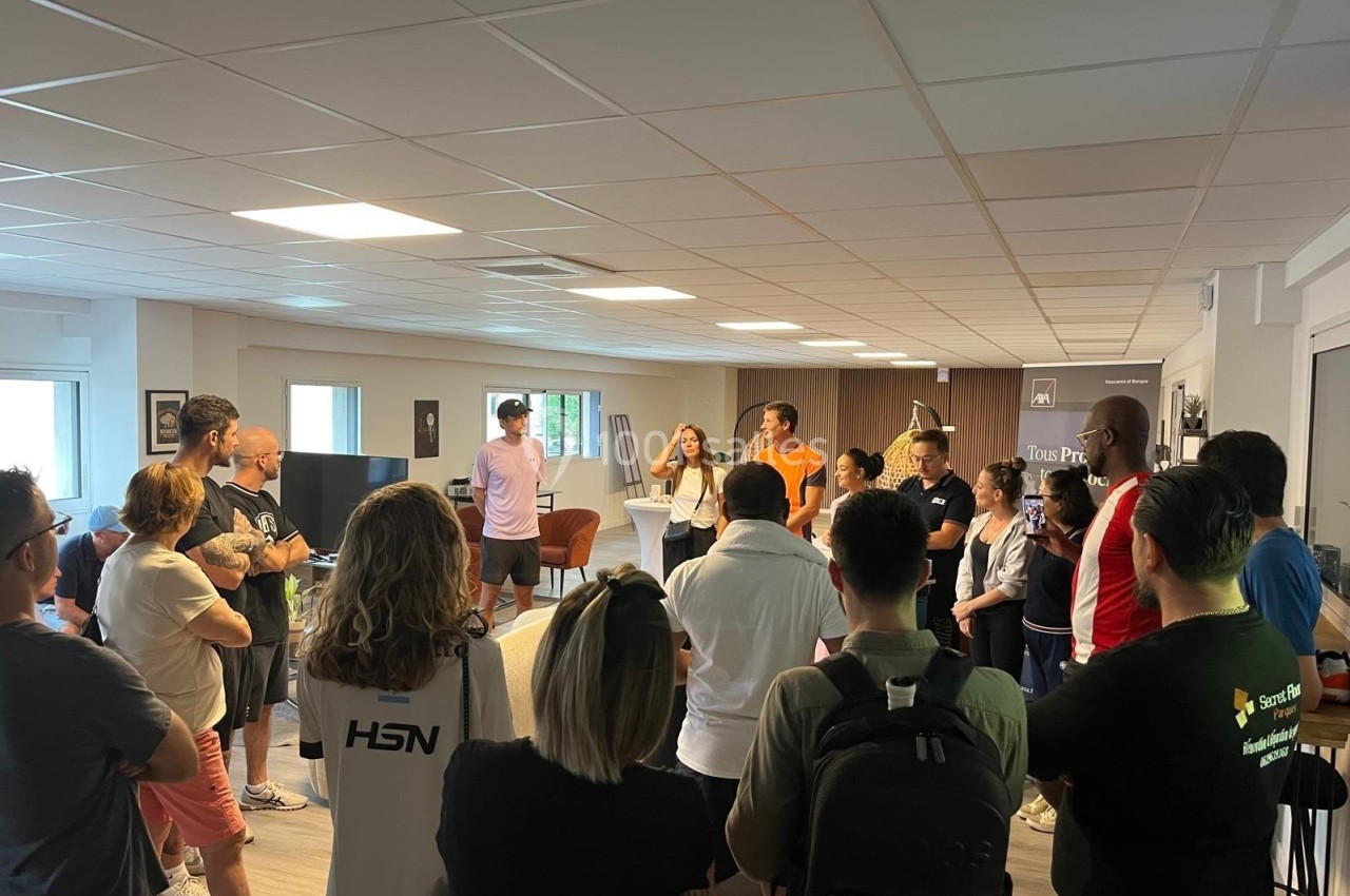 Un groupe de personnes debout dans une salle, écoutant une présentation ou discutant ensemble.