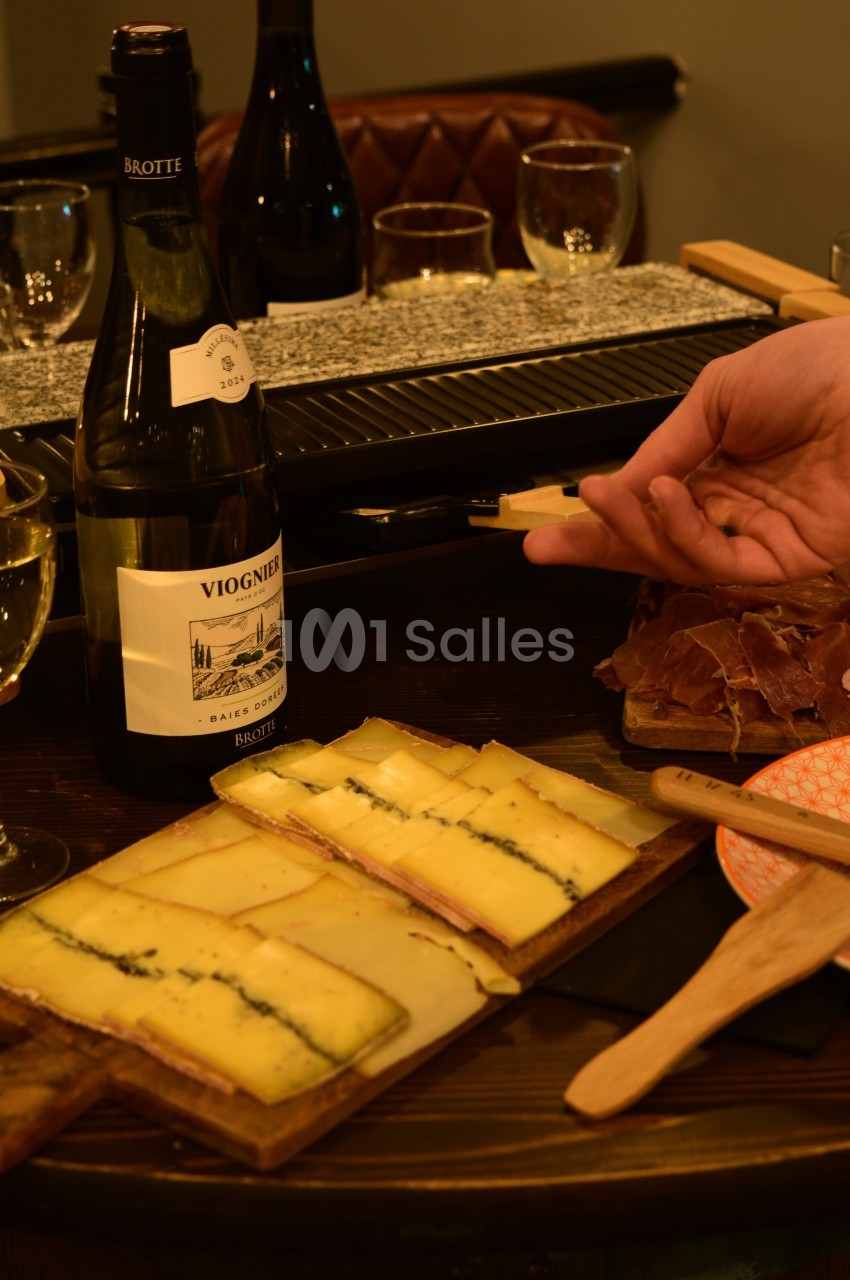 Dégustation de fromages et charcuteries sur planche avec bouteilles de vin et verres.