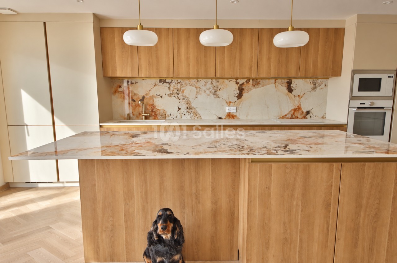 Cuisine contemporaine avec îlot en bois, plan de travail en marbre veiné et pendentifs blancs suspendus.
