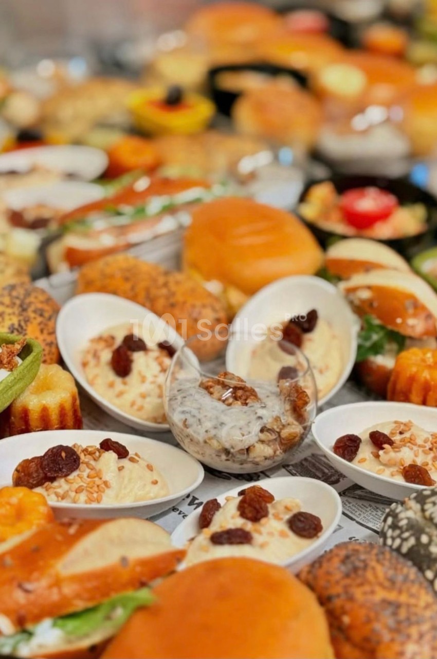 Plateau de buffet garni de petites coupelles blanches de semoule ou crème aux raisins secs et graines de sésame, de sandwichs sur pains briochés et de viennoiseries salées. Wait, I must check constraints: under 125 characters. That sentence is too long.