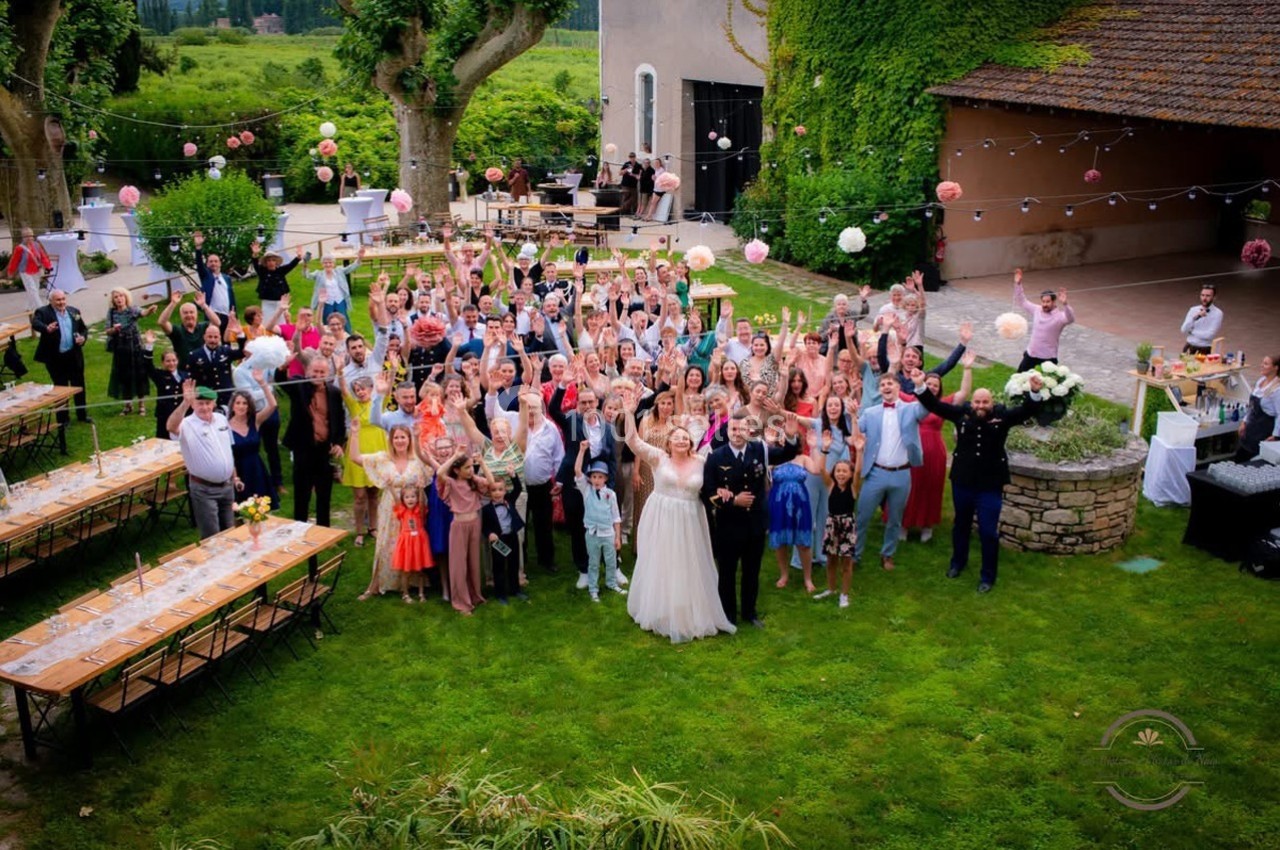 Un groupe de personnes rassemblées dans un jardin pour une célébration, avec des tables dressées et des décorations…