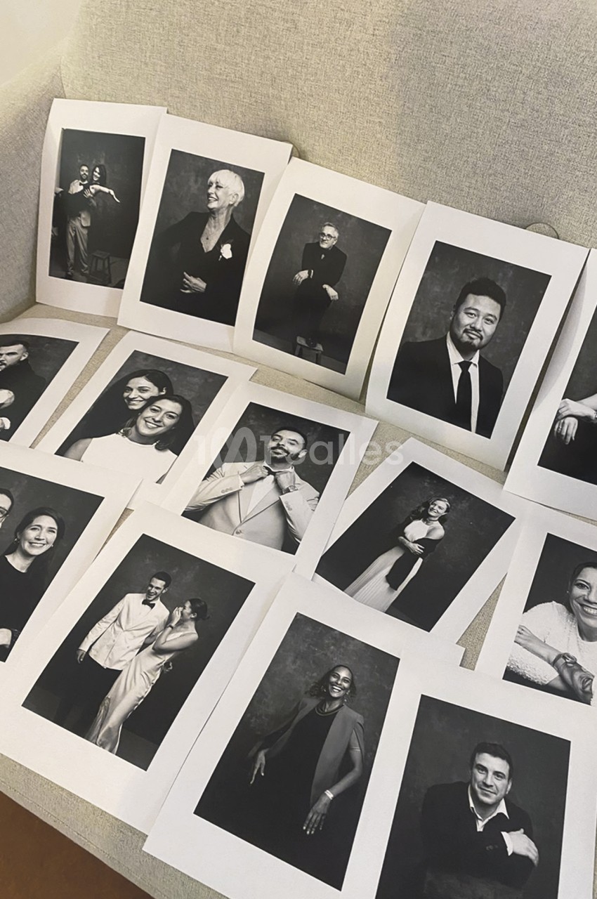 Tirages noir et blanc de portraits de groupes et de couples, posés en désordre sur un canapé, sur fond sombre et cadrage vertical.