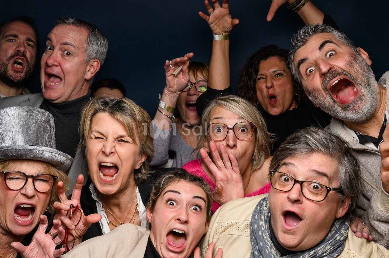 Groupe d'adultes aux expressions exagérées, bouche grande ouverte et yeux écarquillés, posant serrés contre un fond bleu nuit uni.