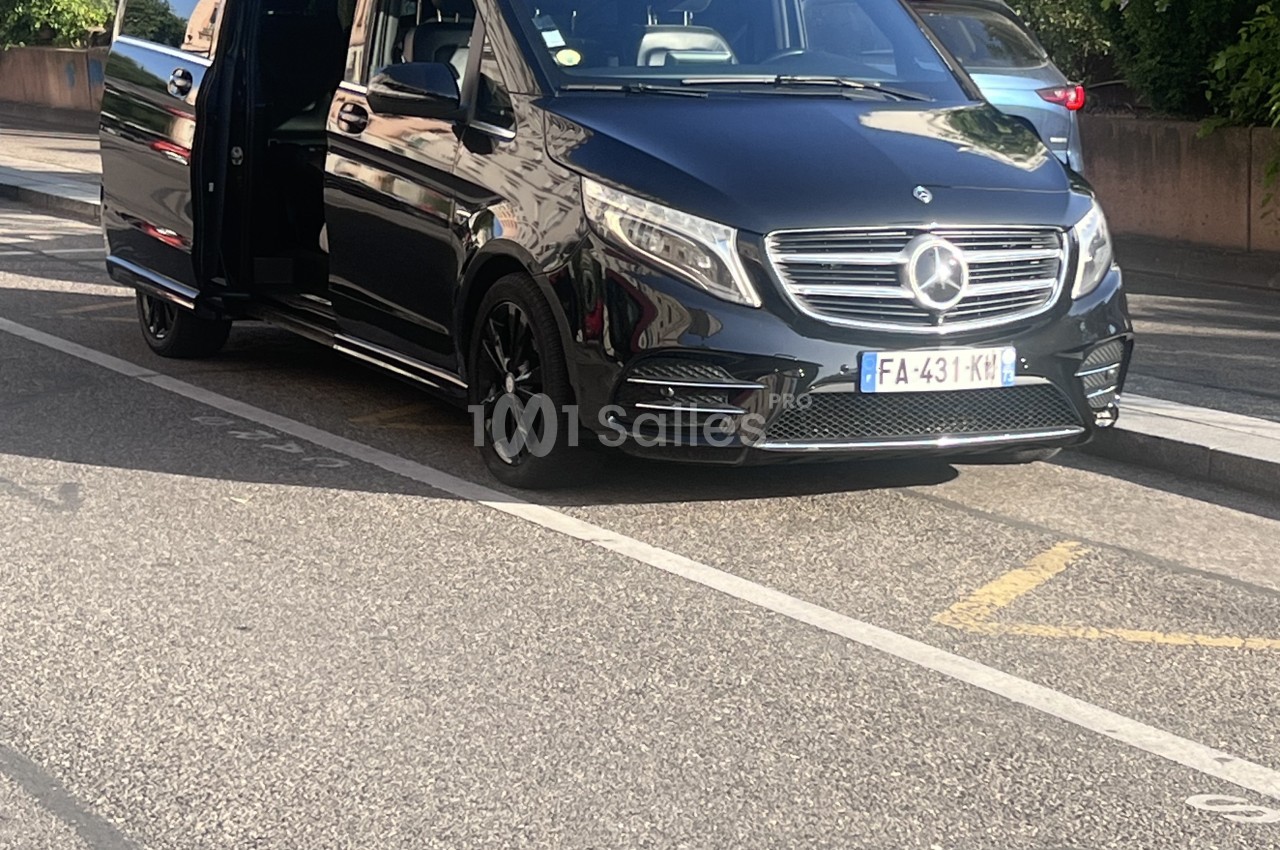 Monospace? No. Need one sentence, ≤125 chars, no "Photo de", no plate text transcription, no watermark text. Image: black minivan Mercedes-style, side door open, parked on street. Context: VTC, Lyon 3. Context can clarify: a VTC vehicle. Avoid