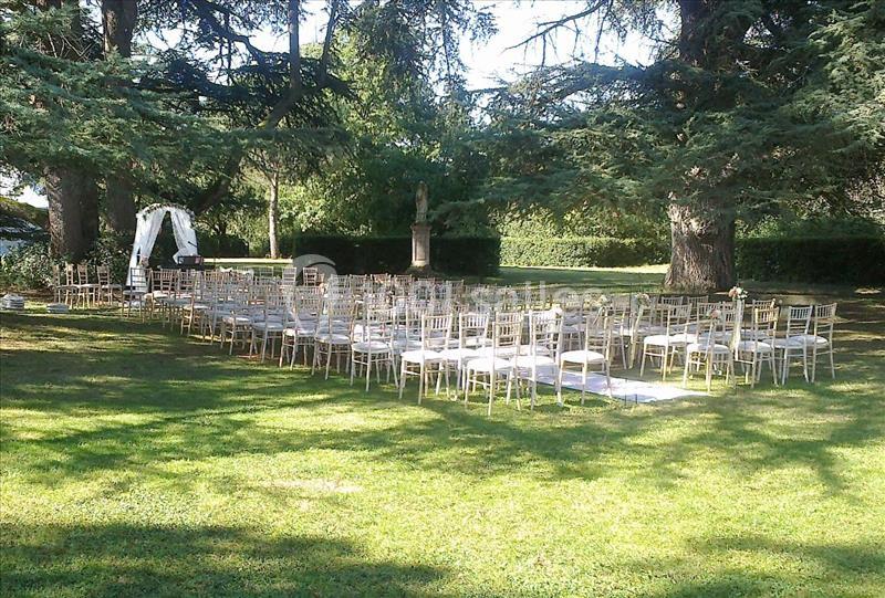 Chaises disposées en rangées sur une pelouse, formant un espace pour une cérémonie en plein air sous des arbres.