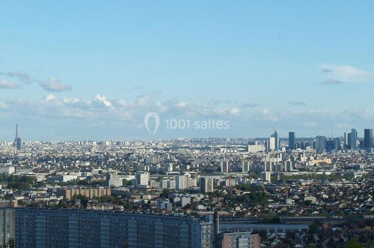 Vue panoramique d'une ville avec la tour Eiffel à gauche et des gratte-ciels modernes à droite sous un ciel dégagé.