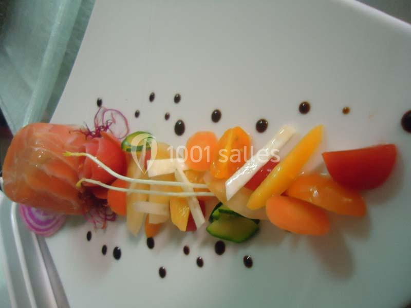 Assiette de légumes colorés et saumon fumé, présentés avec des traits de sauce balsamique sur une assiette blanche.