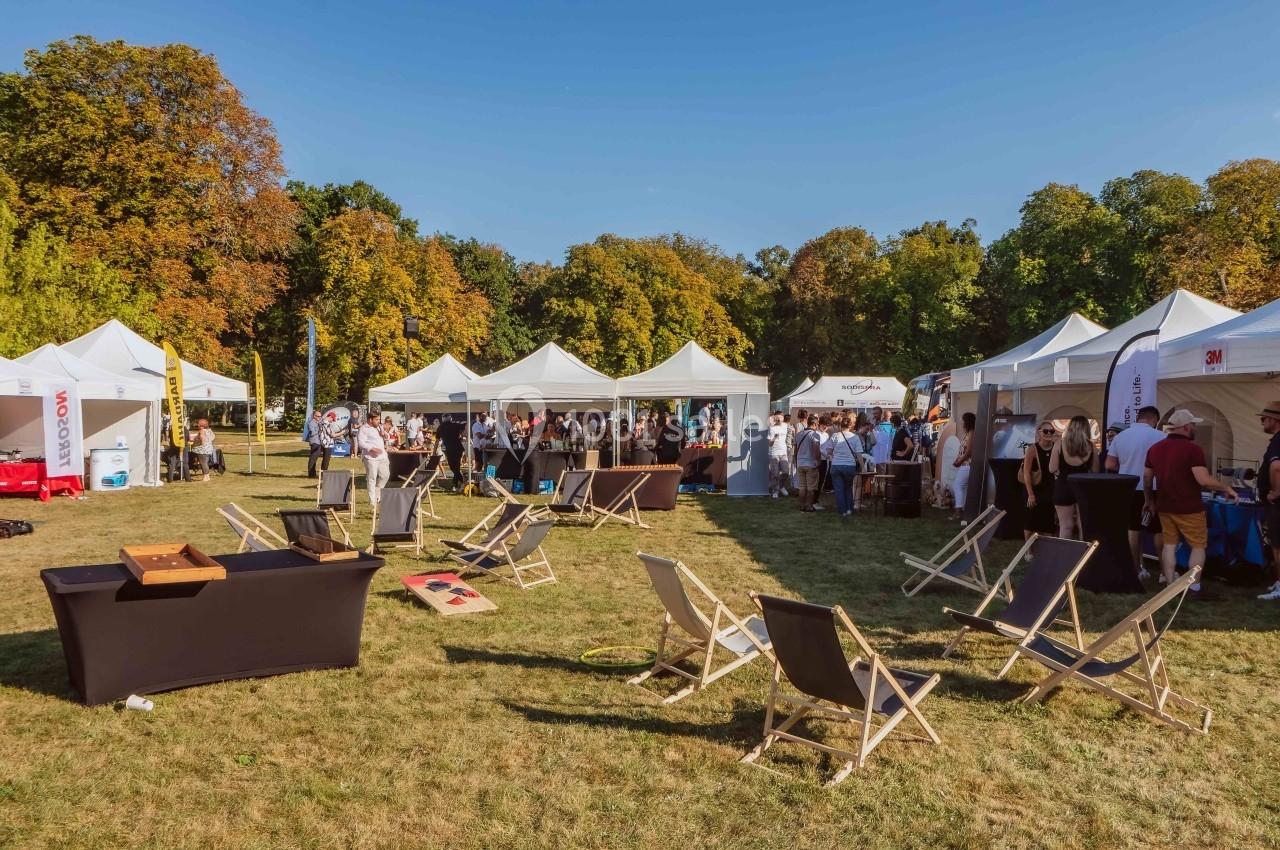Des stands et chaises longues installés sur une pelouse lors d'un événement en plein air par une journée ensoleillée.