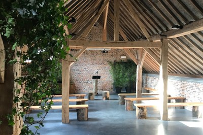Miniature Location salle Pont-à-Celles (Hainaut) - La Ferme du Grand Marcha #24 Salle avec charpente en bois apparente, bancs rustiques en rondins, murs en briques et plantes vertes décoratives.