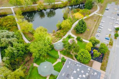 Bâtiment blanc moderne à deux étages avec colonnes, grandes fenêtres et espace paysager à l'avant.