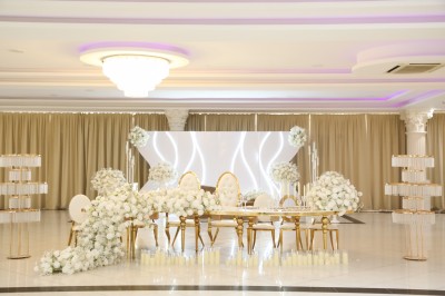 Bâtiment blanc moderne à deux étages avec colonnes, grandes fenêtres et espace paysager à l'avant.