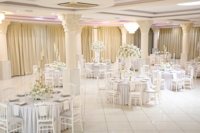 Bâtiment blanc moderne à deux étages avec colonnes, grandes fenêtres et espace paysager à l'avant.