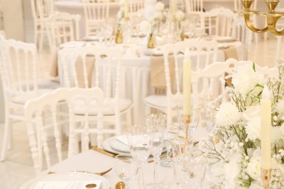 Bâtiment blanc moderne à deux étages avec colonnes, grandes fenêtres et espace paysager à l'avant.