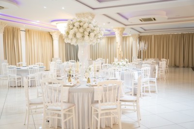 Bâtiment blanc moderne à deux étages avec colonnes, grandes fenêtres et espace paysager à l'avant.