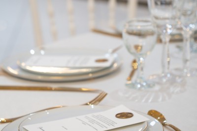 Bâtiment blanc moderne à deux étages avec colonnes, grandes fenêtres et espace paysager à l'avant.