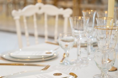 Bâtiment blanc moderne à deux étages avec colonnes, grandes fenêtres et espace paysager à l'avant.