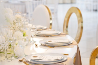 Bâtiment blanc moderne à deux étages avec colonnes, grandes fenêtres et espace paysager à l'avant.