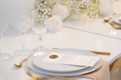 Bâtiment blanc moderne à deux étages avec colonnes, grandes fenêtres et espace paysager à l'avant.