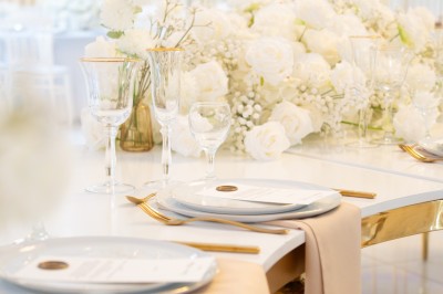 Bâtiment blanc moderne à deux étages avec colonnes, grandes fenêtres et espace paysager à l'avant.