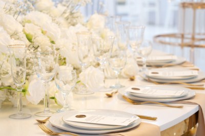 Bâtiment blanc moderne à deux étages avec colonnes, grandes fenêtres et espace paysager à l'avant.