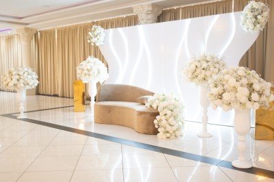 Bâtiment blanc moderne à deux étages avec colonnes, grandes fenêtres et espace paysager à l'avant.