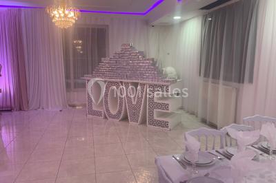 Buffet de desserts avec macarons colorés, verrines et pâtisseries disposés sur des présentoirs décoratifs dans une salle…