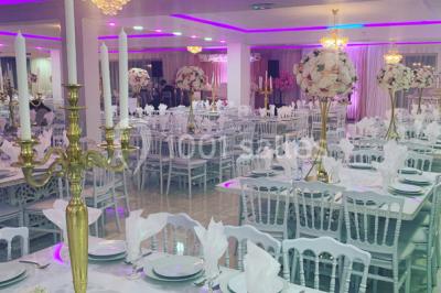 Buffet de desserts avec macarons colorés, verrines et pâtisseries disposés sur des présentoirs décoratifs dans une salle…