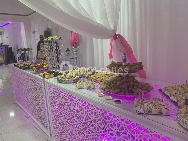 Buffet varié avec pâtisseries, amuse-bouches et plats salés, présenté sur une table décorée de motifs ajourés.