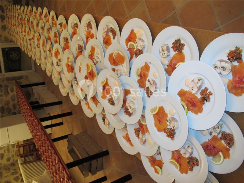 Assiettes alignées contenant du saumon fumé, des tranches de citron, une sauce et une garniture sur une longue table.