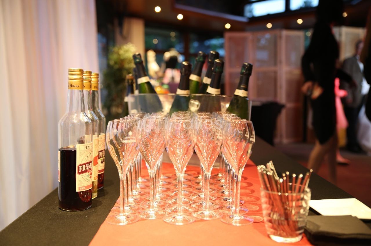 Bouteilles de liqueur et de champagne alignées avec des verres à pied sur une table lors d'un événement intérieur.