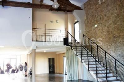 Salle à manger lumineuse avec table en bois, chaises colorées, cuisine ouverte et décoration sobre.