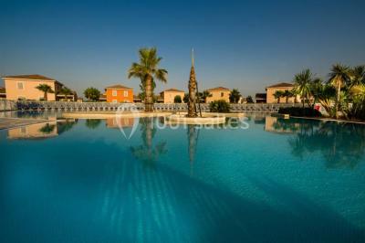 Salle à manger lumineuse avec table en bois, chaises colorées, cuisine ouverte et décoration sobre.