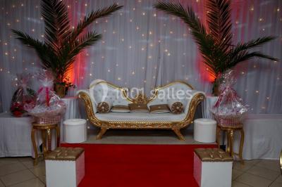 Miniature Salle de réception jusqu’à 120 personnes avec coin des mariés, piste de danse, loge des mariés Canapé doré et blanc décoré, entouré de palmiers, de cadeaux emballés et éclairé par des lumières tamisées.