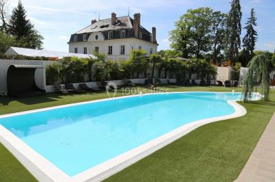 Salle de bain avec une cabine de douche moderne, un banc en bois intégré, deux vasques noires et une fenêtre avec stores.