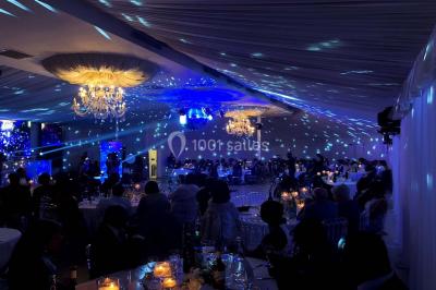 Salle de bain avec une cabine de douche moderne, un banc en bois intégré, deux vasques noires et une fenêtre avec stores.