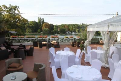 Salle de bain avec une cabine de douche moderne, un banc en bois intégré, deux vasques noires et une fenêtre avec stores.