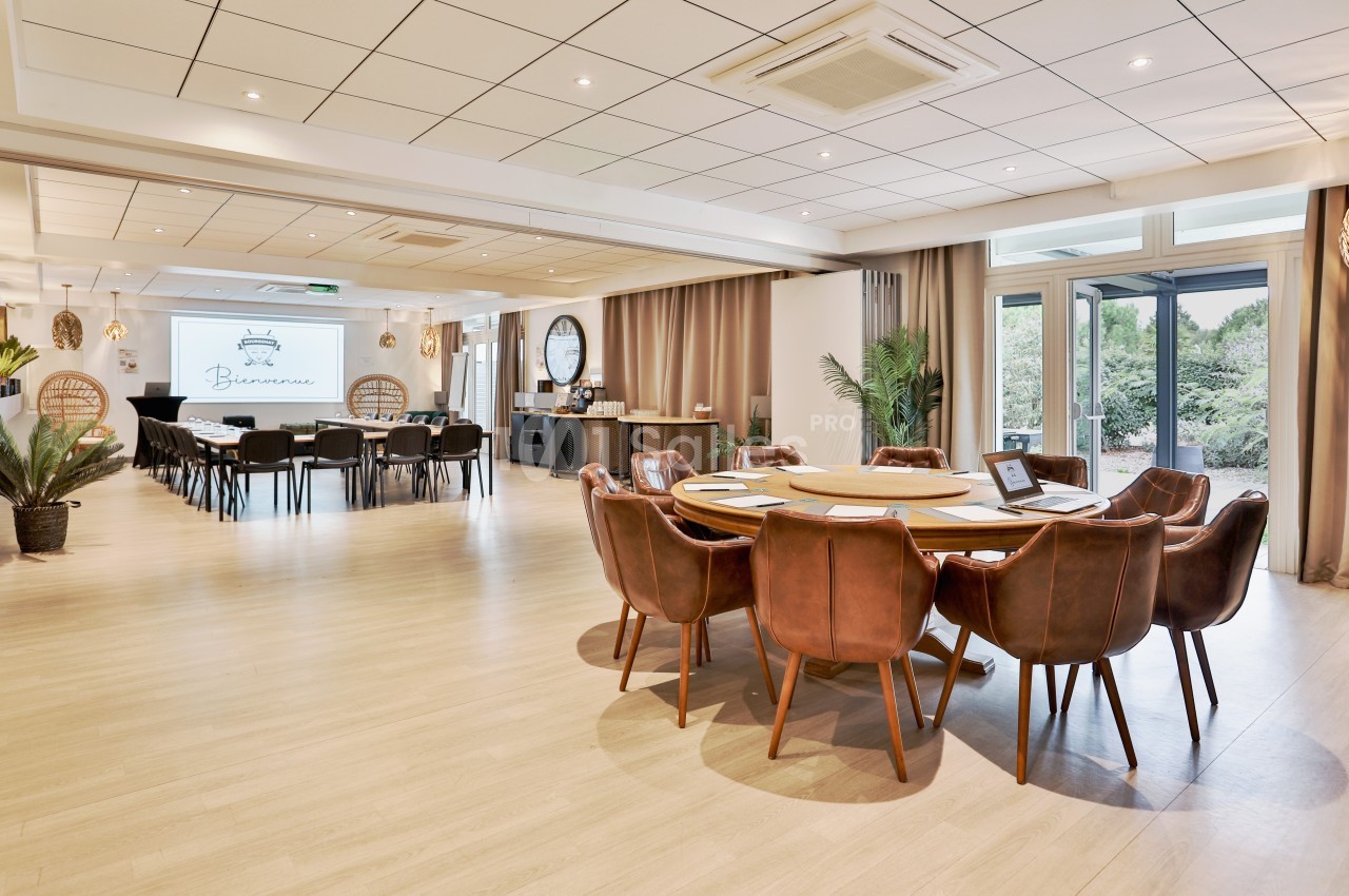 Salle de réunion lumineuse avec tables en bois, chaises en cuir, écran de présentation et grandes baies vitrées donnant sur…