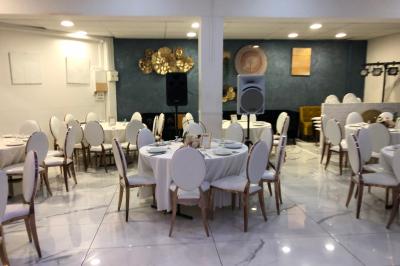 Salle décorée avec des tables rondes dressées, nappes blanches, chaises élégantes et centre de table floral.