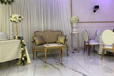 Salle décorée avec des tables rondes dressées, nappes blanches, chaises élégantes et centre de table floral.