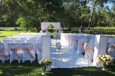 Miniature Location salle Arbonne-la-Forêt (Seine-et-Marne) - Le Domaine du Rocher #3 Allée gravillonnée bordée de verdure et de plantes, menant à une entrée avec des arches blanches sous un ciel dégagé.