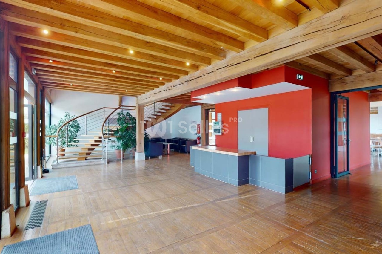 Intérieur d'un espace lumineux avec plafond en bois, escalier moderne, murs rouges et grandes fenêtres vitrées.