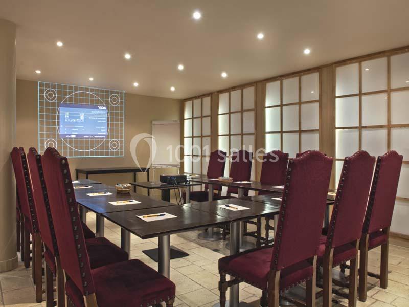 Salle de réunion équipée avec une grande table, des chaises rouges, un projecteur et un écran affichant un test d'image.