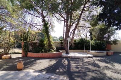 Vue aérienne d'une maison avec toit en tuiles, piscine rectangulaire et jardin arboré dans un cadre rural.