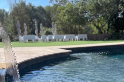 Vue aérienne d'une maison avec toit en tuiles, piscine rectangulaire et jardin arboré dans un cadre rural.