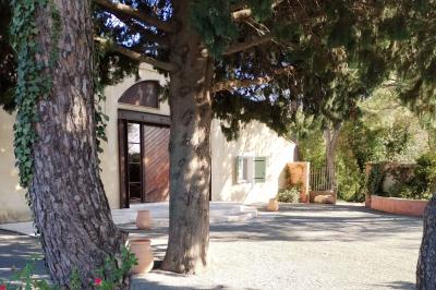 Vue aérienne d'une maison avec toit en tuiles, piscine rectangulaire et jardin arboré dans un cadre rural.