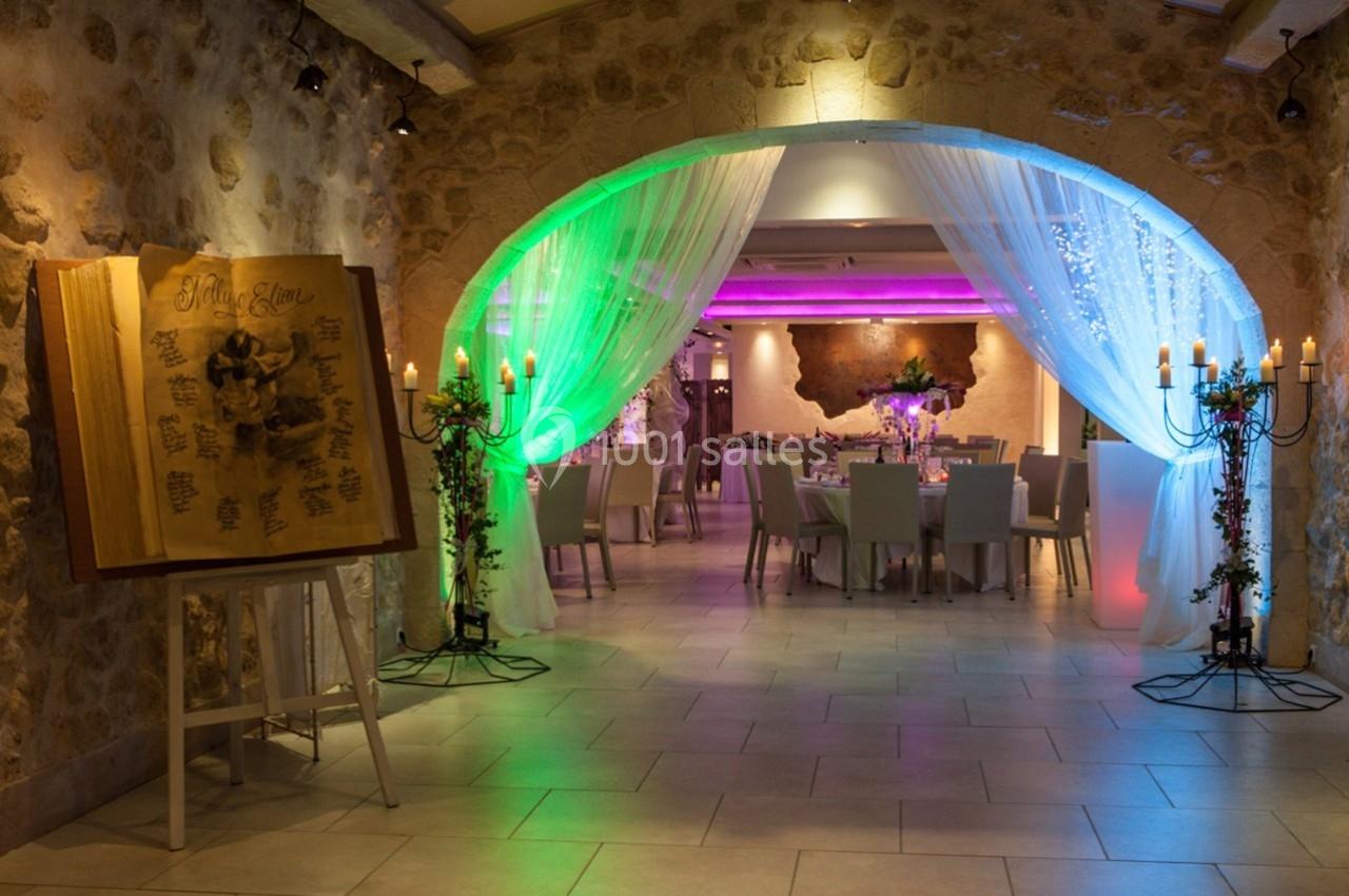 Salle de réception décorée avec des tables dressées, éclairage coloré et un grand livre d'honneur sur un chevalet.